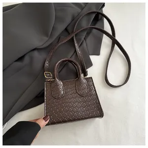 Detail of dark brown faux crocodile leather mini tote with gold hardware and top handles