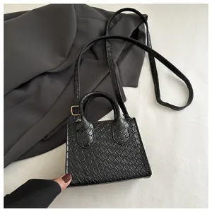 Close-up of black woven texture handbag with gold buckle and adjustable strap