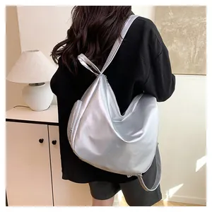 Side view of a futuristic silver metallic backpack worn by a model in a minimalist room