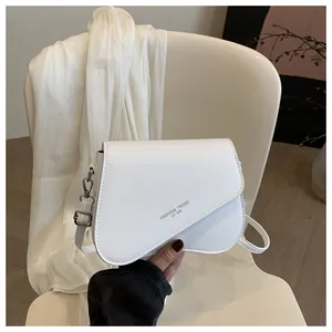 Detailed view of the white asymmetrical flap bag featuring silver fashion trend logo print