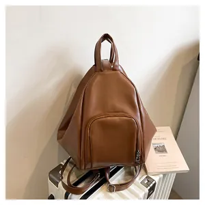 Close-up of brown PU leather teardrop backpack with front zipper pocket and top handle