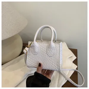 Detail of white embossed crocodile pattern handbag with elegant gold hardware accents