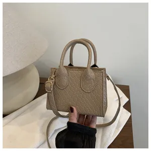 Detailed macro view of the beige faux leather square bag with elegant crocodile texture