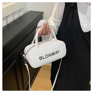 Detail of white baguette bag with BLONMAY text, woven texture, and top handle