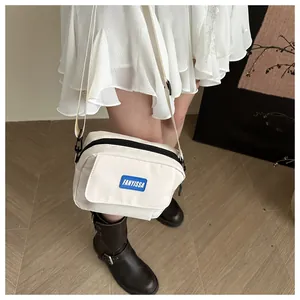 Photo de sac bandoulière en toile blanche avec étiquette bleue et sangle réglable