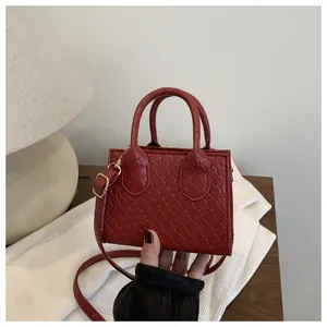 Detail of red woven texture on a mini crossbody bag with golden hardware and top handles