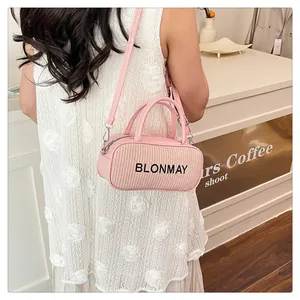 Pink woven baguette bag shown on shoulder with stylish dress in a cafe setting