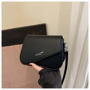 Detail of matte black PU leather shoulder bag with asymmetrical curved flap and silver logo