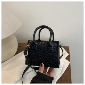 Close-up of black crossbody bag featuring detailed crocodile texture and gold hardware