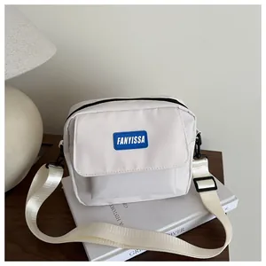 Détail du sac bandoulière blanc en nylon avec logo bleu et boucle métallique noire