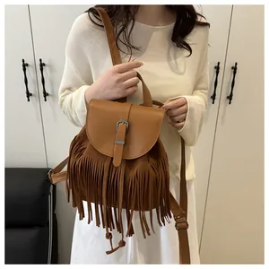 Detail of a brown fringe backpack with metal buckle closure and textured faux leather finish