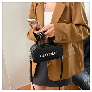Detail of woven texture and BLONMAY logo on black baguette bag held by a model