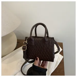 Detail of dark brown mini crossbody bag featuring woven texture and gold hardware