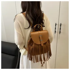 Back view of model wearing a brown fringe bucket backpack with bohemian tassel details