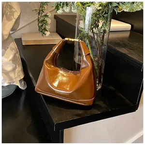 Detail of caramel leather handbag with gold buckle on elegant dark stairs with flowers