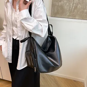 Minimalist black PU leather shoulder bag with side zipper pocket shown on a model