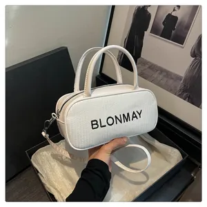 Detail of off-white baguette bag with woven texture and dual handles in a gift box