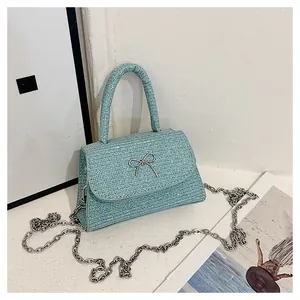 Close-up of light blue textured handbag with silver bow detail and elegant metal chain