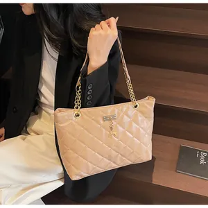 Detail of beige quilted tote bag with golden chain strap and a small deer charm pendant