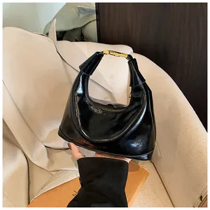 Detail of black glossy croissant bag with gold buckle and embossed fashion text
