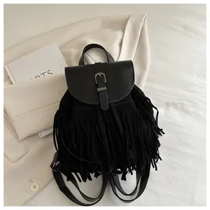 Detail shot of black fringe backpack with metal buckle and leather straps on white blazer