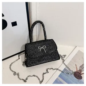 Close-up of black sequined butterfly bag featuring silver bow detail and metallic chain