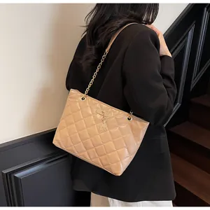 Detail of light brown quilted tote bag with golden chain strap and deer charm