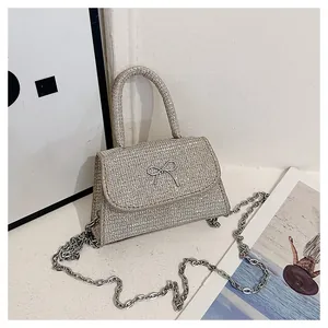 Close-up of a silver sequined handbag featuring a metallic bow and chain strap