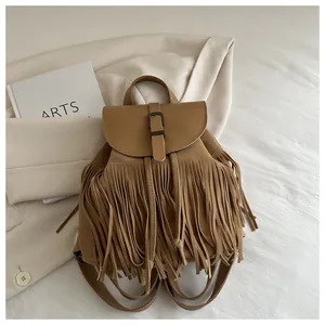 Close-up of tan tassel bucket bag with vintage metal buckles on a minimalist background
