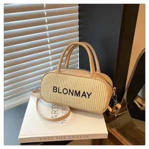 Detail view of beige woven straw and leather baguette bag with silver zipper hardware