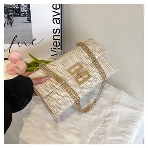 Detail of woven straw handbag with gold H-buckle and metal chain strap in cream white