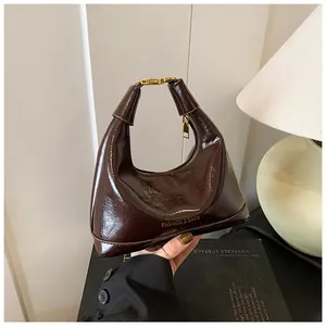 Detail of dark brown glossy patent leather bag with gold hardware and fashion logo