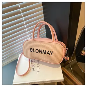 Detailed shot of pink leather baguette bag with woven straw panel and black embroidery
