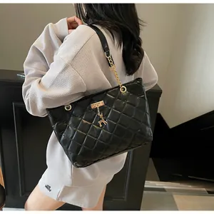 Close-up of black quilted tote bag featuring golden chain straps and deer charm detail