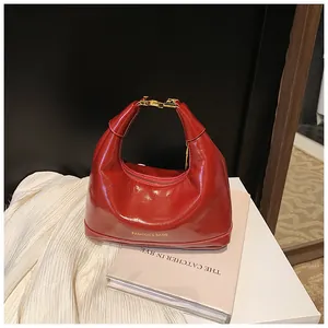 Detail of red patent leather dumpling bag with gold buckle and fashion text logo