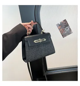 Detail of black glitter and leather handbag with gold metal lock held by a model