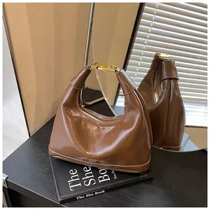 Detail of dark brown leather handbag featuring a large gold metal buckle and gold logo