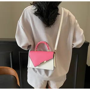Dettaglio borsa a contrasto rosa e bianca con manico a treccia e finiture in metallo dorato