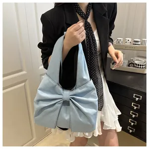 Détail du sac à épaule en jean bleu clair avec un grand nœud décoratif et bandoulière