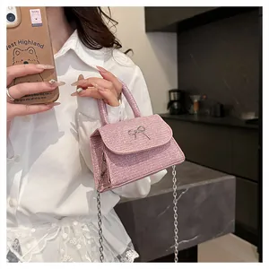 Pink sequin mini bag with silver butterfly detail and chain strap shown in lifestyle use