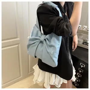 Sac fourre-tout en denim bleu clair avec grand nœud porté par un mannequin élégant