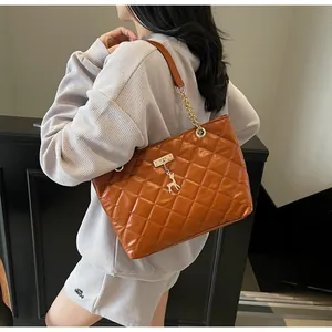 Detail of brown quilted tote bag with gold chain strap and deer charm on shoulder