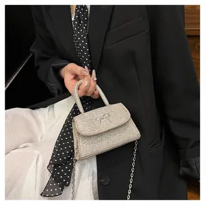 Silver glitter mini bag with metal bow detail and chain strap held by a model