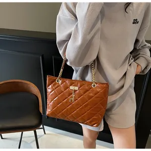 Detail of brown quilted leather shoulder bag with gold chain and deer pendant charm