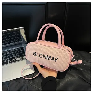 Detail of pink baguette bag with Blonmay embroidery and woven texture on a desk