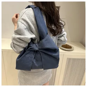 Détail du sac à épaule en jean bleu foncé avec un grand nœud et un design spacieux