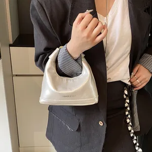 Silver metallic mini hobo bag with top handle shown on model in a stylish suit