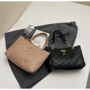 Close-up of quilted tote bags in beige and black with golden chain handles and deer charm