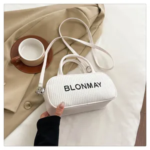 Close-up of the white baguette bag with woven texture, silver hardware and logo detail