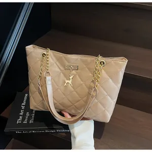 Detail of beige quilted tote bag featuring a gold chain strap and cute deer charm